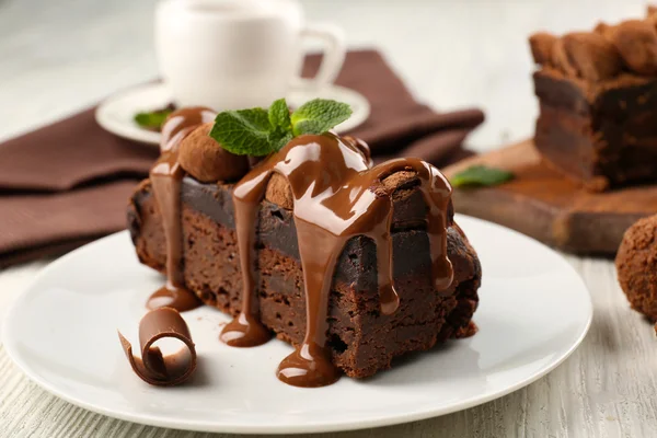 A piece of chocolate cake with mint on the table, close-up