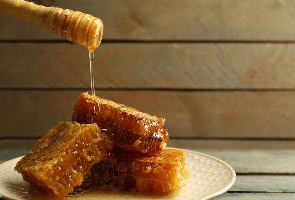 Honing druipend op honingraten, op houten achtergrond — Stockfoto