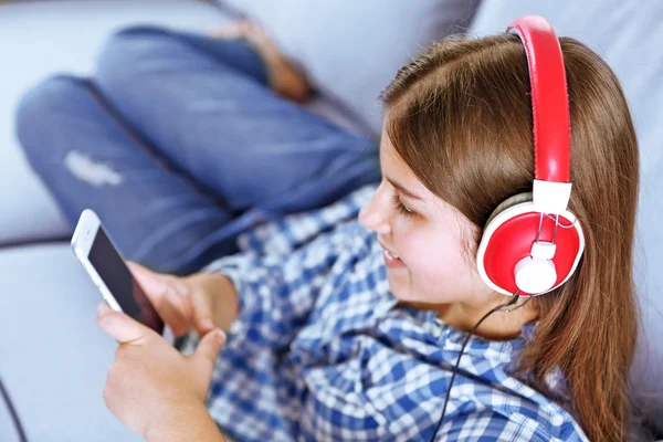 Linda chica escuchando música en el sofá —  Fotos de Stock