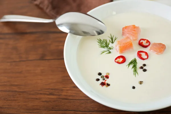 Delicious salmon cream soup with spoon on wooden table, close up — Stock Photo, Image