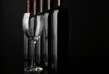 Cam ve şarap şişeleri üst üste siyah arka plan üzerinde kapat