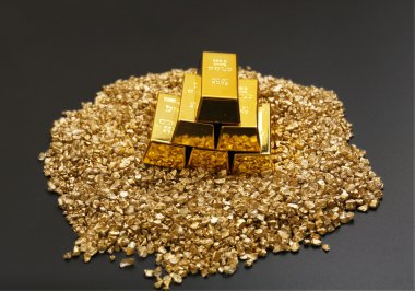 Altın külçeleri ve gri arka plan üzerinde nugget taneleri