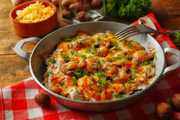 Cogumelos assados, frango e queijo gratinado em panela, sobre fundo de madeira — Fotografia de Stock