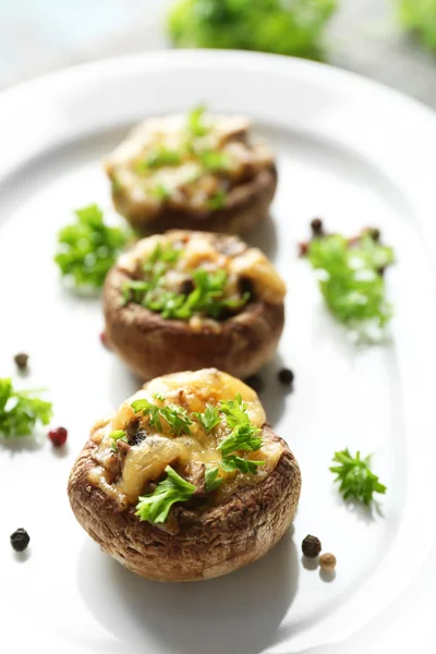 Stuffed mushrooms on plate, on table background