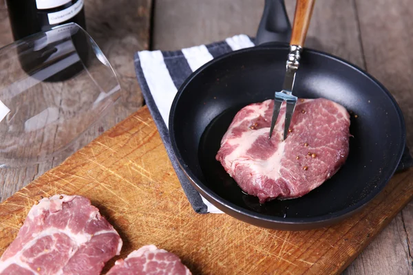 Bife de carne marmorizada e garrafa de vinho no fundo de madeira — Fotografia de Stock