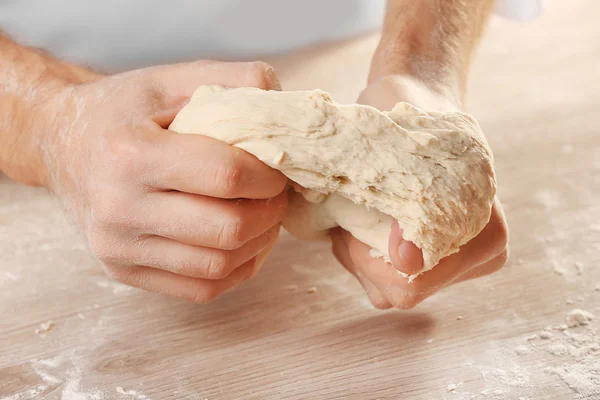 Manos amasando masa para pizza en la mesa de madera, primer plano — Foto de Stock