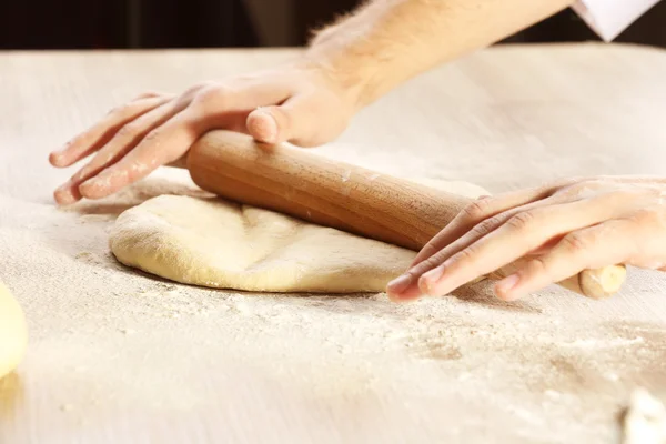 Ręce toczenia ciasta na pizzę na drewnianym stole, zbliżenie — Zdjęcie stockowe