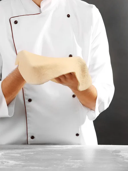 Mann bereitet Teigbasis für Pizza auf dem Holztisch vor, Nahaufnahme — Stockfoto