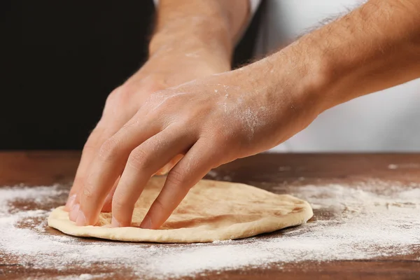 Hands preparing dough basis for pizza on the wooden table, close-up — Stock Photo, Image