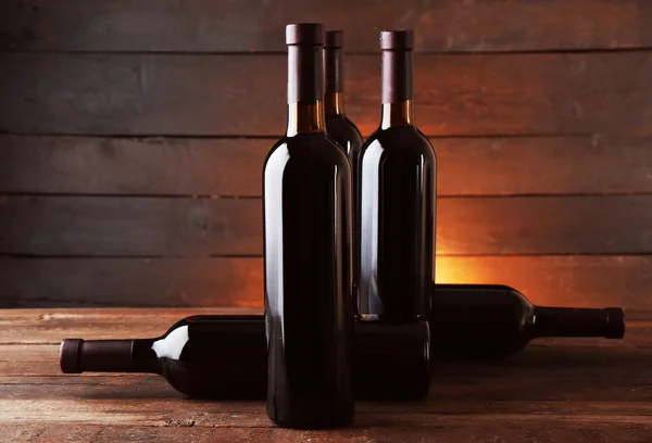 Weinflaschen auf dem Tisch vor Holzhintergrund — Stockfoto