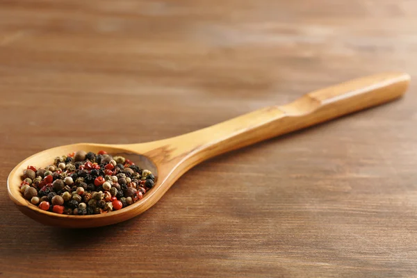 Cuchara de madera con pimienta en la mesa, primer plano — Foto de Stock