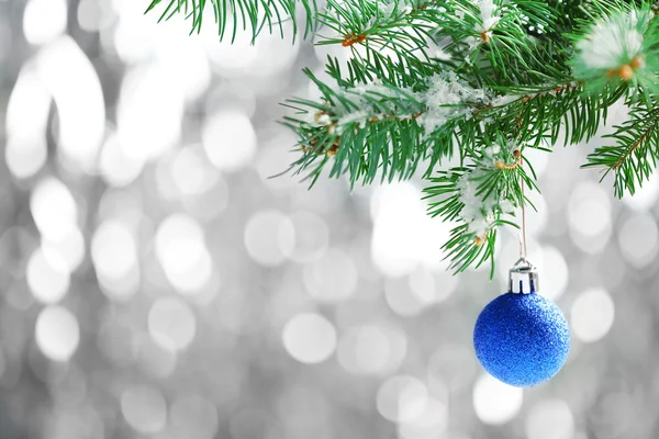 Рождественская голубая безделушка на еловой ветке и блестящем фоне Стоковая Картинка