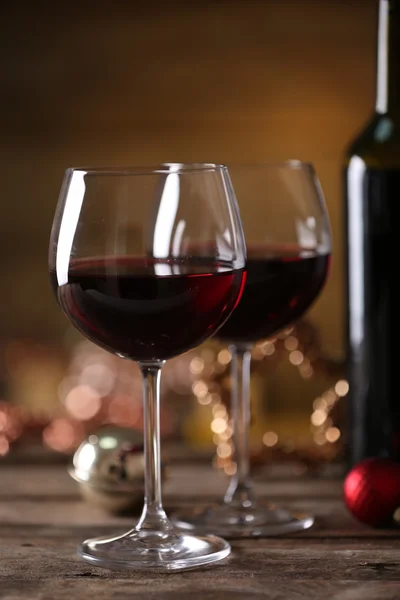 Κόκκινο κρασί και χριστουγεννιάτικα στολίδια στο ξύλινο τραπέζι σε ξύλινα φόντο — Φωτογραφία Αρχείου
