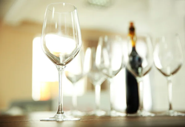 Empty wine glasses with bottle on wooden table against blurred background — Stock Photo, Image