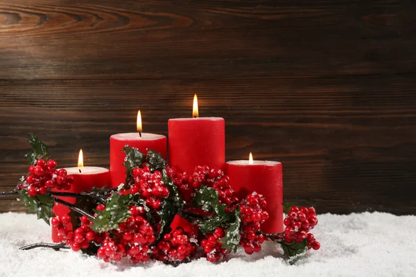 Candele rosse e ramo di bacche di agrifoglio in una neve su sfondo di legno, natura morta — Foto Stock