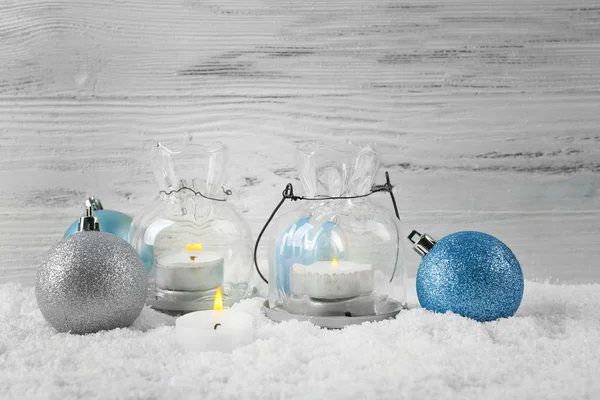 Kaarsen en kerstballen in een sneeuw op houten achtergrond, stilleven — Stockfoto