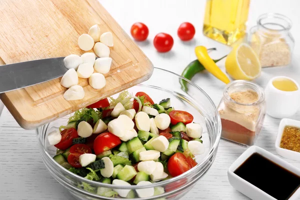 Adicionar queijo mussarela à salada, na cozinha — Fotografia de Stock