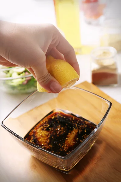 Prozess der Zubereitung von Sauce für Salat, in der Küche. Frauenhände pressen Saft aus Zitrone — Stockfoto