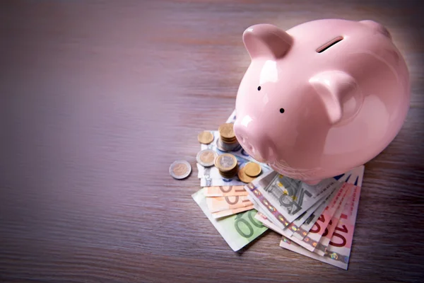 Caja de dinero de cerdo con billetes y monedas en euros —  Fotos de Stock