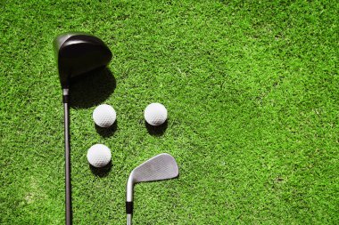 Golf kulüpleri ve top yeşil çimenlerin üzerinde