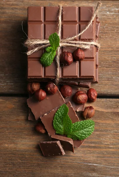Fekete csokoládé darab dió fából készült háttér — Stock Fotó