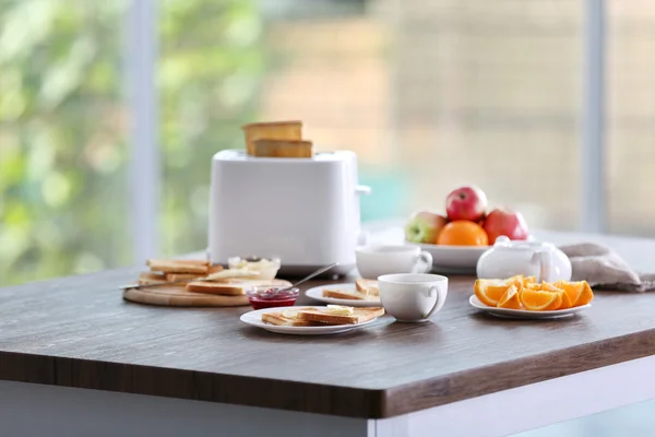 Serveras tabell för frukost med toast, kaffe och frukt, på suddig bakgrund — Stockfoto