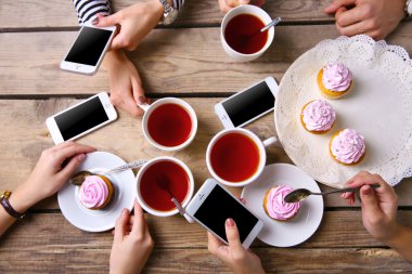 Bardak çay, ahşap masa arka planda tutarak akıllı telefonlar ile dört el