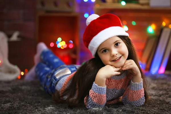 Linda niña en el sombrero rojo que pone en la habitación decorada de Navidad —  Fotos de Stock