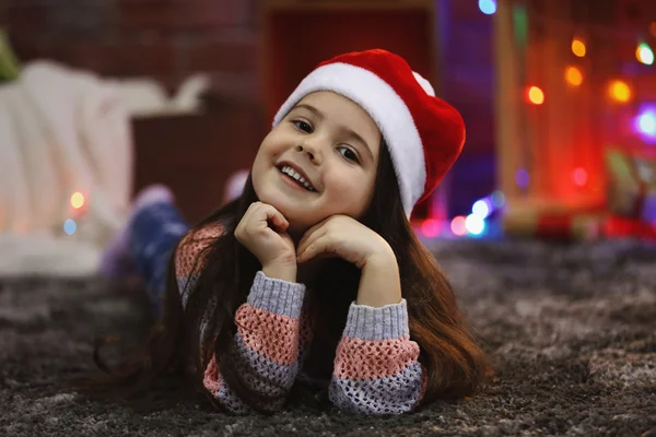 Linda niña en el sombrero rojo que pone en la habitación decorada de Navidad —  Fotos de Stock