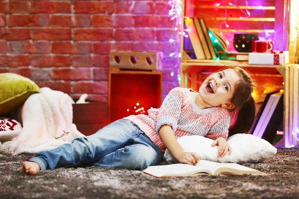 Menina bonita com livro no quarto decorado de Natal — Fotografia de Stock