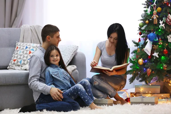 Feliz familia leer el libro en la habitación de Navidad decorada — Foto de Stock