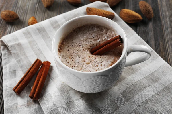 Cup of hot cacao on cotton serviette with cinnamon and almonds — Stock Photo, Image