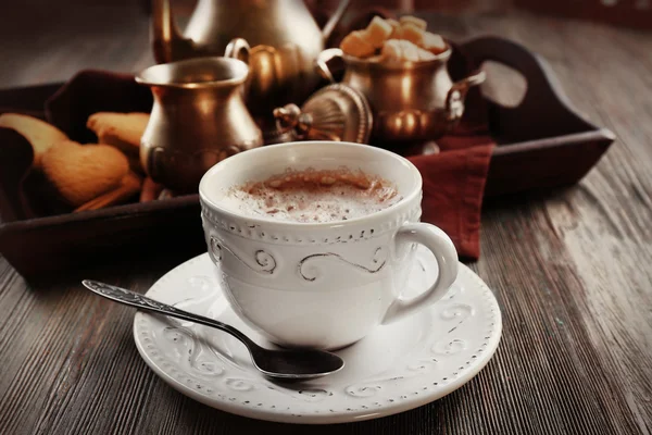 Vintage tazza di cacao su tavolo in legno contro vassoio con servizio argento e biscotti — Foto Stock