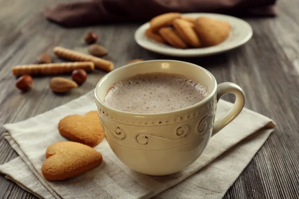 Secangkir coklat panas pada serbet kapas dengan kayu manis, almond dan kue berbentuk hati — Stok Foto