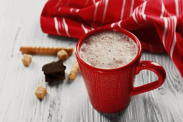 Cangkir merah coklat panas dan permen di latar belakang kayu — Stok Foto