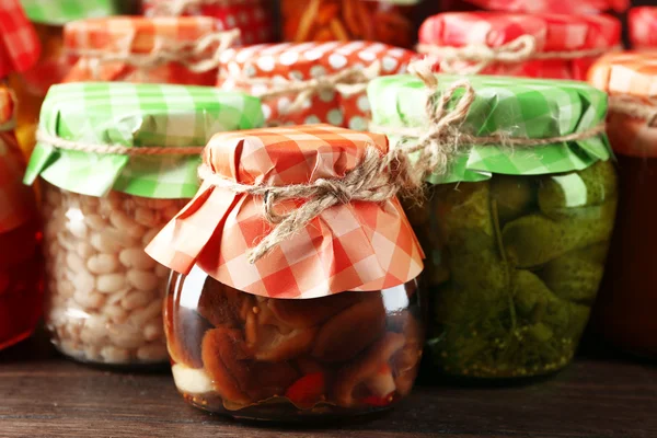 Jars with pickled vegetables and beans on wooden background — Stock Photo, Image