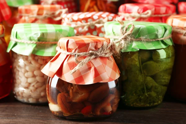 Frascos con verduras y frijoles en vinagre sobre fondo de madera — Foto de Stock