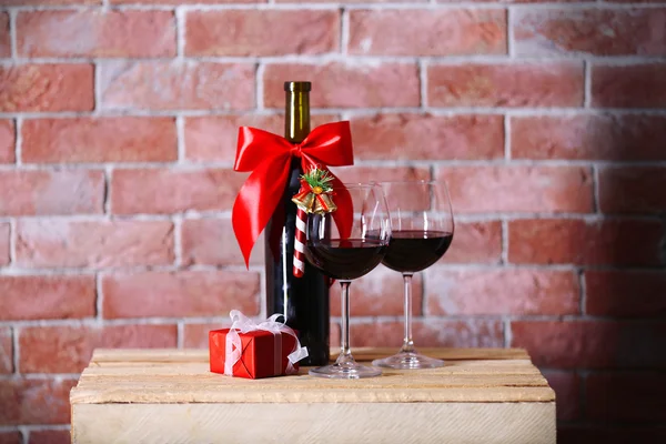 Μπουκάλι κόκκινο κρασί και γυαλιά με τα δώρα Χριστουγέννων σε φόντο τοίχο — Φωτογραφία Αρχείου