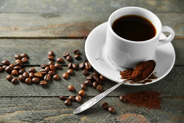 Чашка кави та зерна кави на дерев'яному столі, на сірому фоні — стокове фото