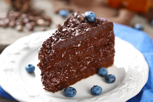 Gâteau au chocolat avec crème au chocolat et bleuets frais sur assiette, sur fond en bois — Photo