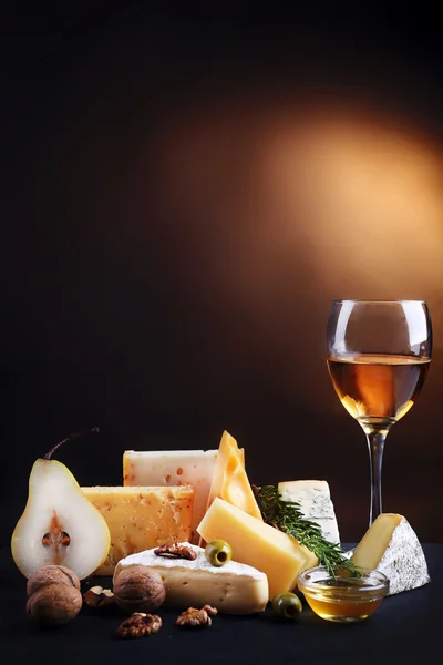 Різні види сиру, келих для вина, груша, горіхи та оливки, на столі, крупним планом — стокове фото