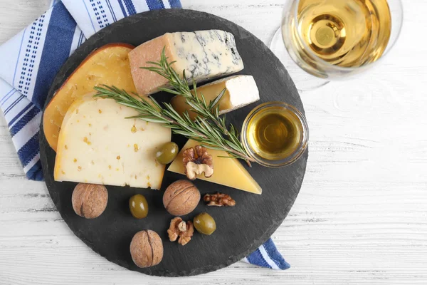 Mesa de madera servida con vino y diferentes tipos de queso y nueces en la mesa redonda — Foto de Stock