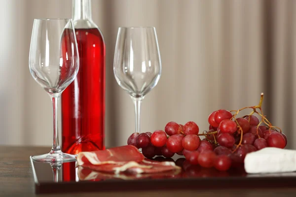 Roze fles wijn, twee wijnglazen, druif, sneetjes spek en kaas op een tafel, stilleven — Stockfoto