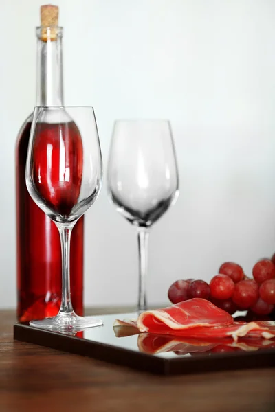 Pink wine bottle, two wineglasses, grape, slice of bacon on a table, still life — Stock Photo, Image