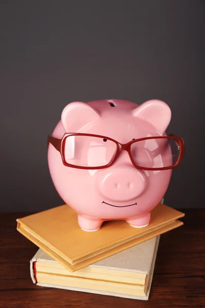 Piggy bank met glazen en boeken — Stockfoto