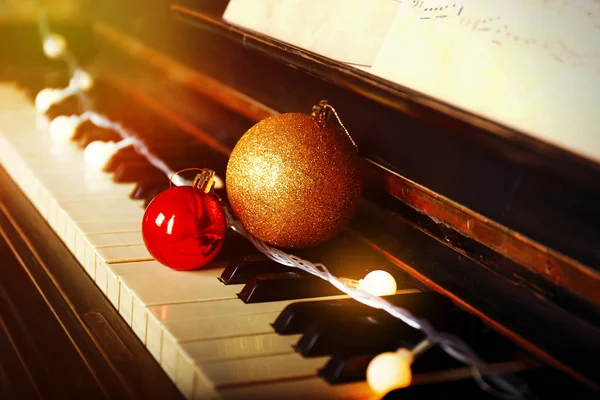 Piano keys decorated with decorative lights and balls, close up — Stock Photo, Image