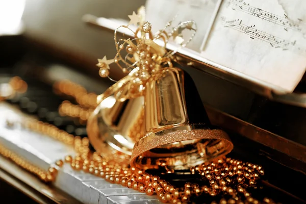 Piano keys decorated with golden Christmas decorations, close up — Stock Photo, Image