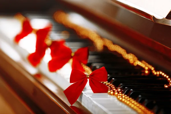 Piano keys decorated with golden Christmas decorations, close up — Stock Photo, Image