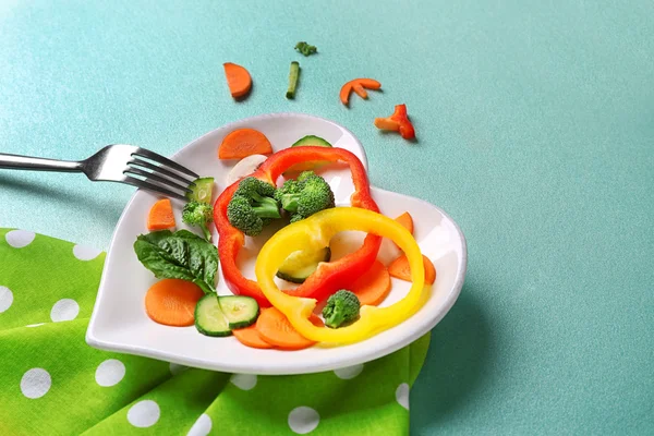 Nuttig gesneden groenten op een bord in de vorm van hart op houten tafel bovenaanzicht — Stockfoto