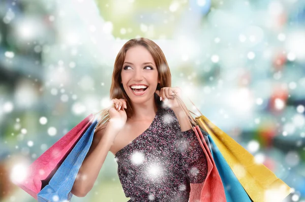 Mulher bonita com sacos no centro comercial sobre efeito de neve — Fotografia de Stock